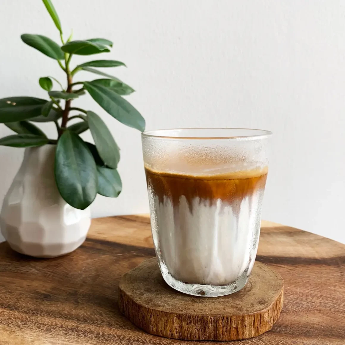 a glass of dirty coffee on a wood coaster