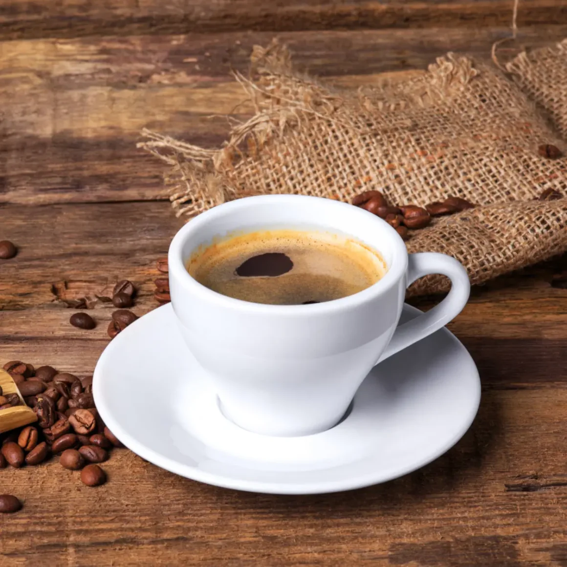 a cup of coffee on a saucer and a sack of medium roast coffee beans