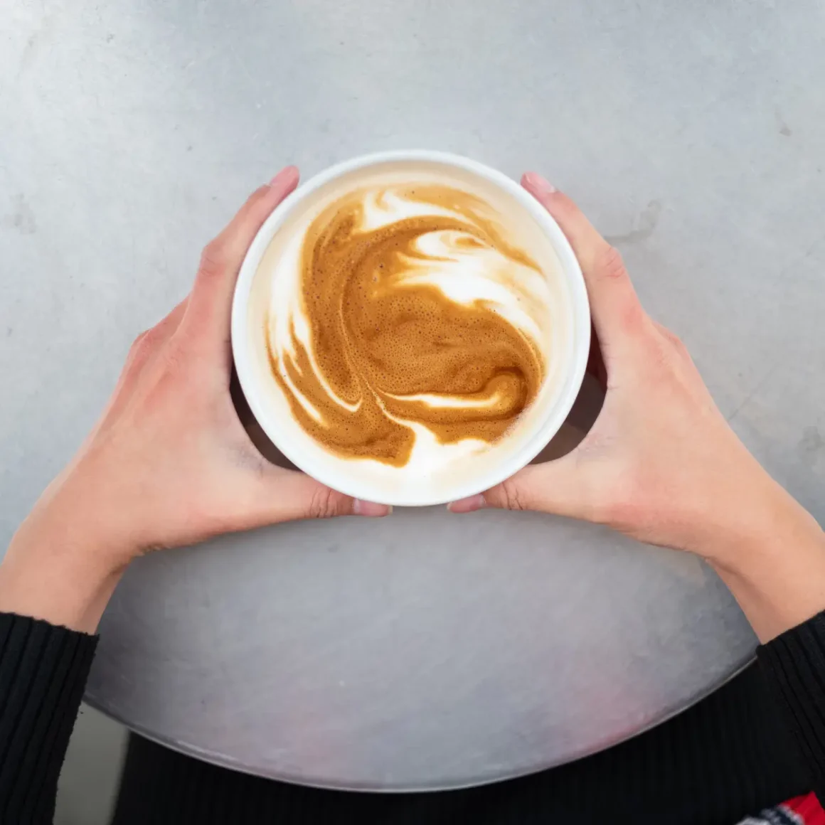 a person holding a cup of caffe misto