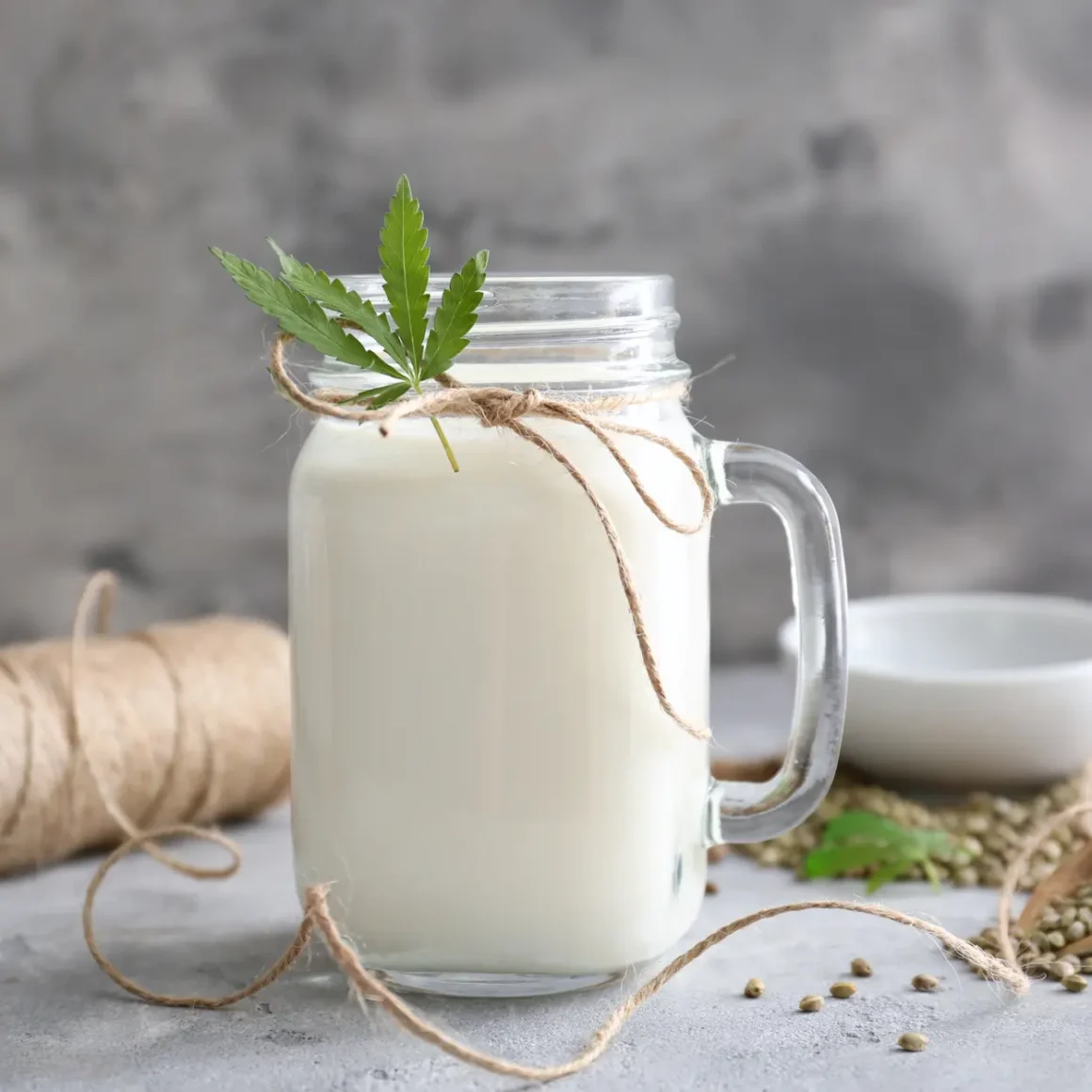 a glass jar with a forthed milk and a hemp leaf on top