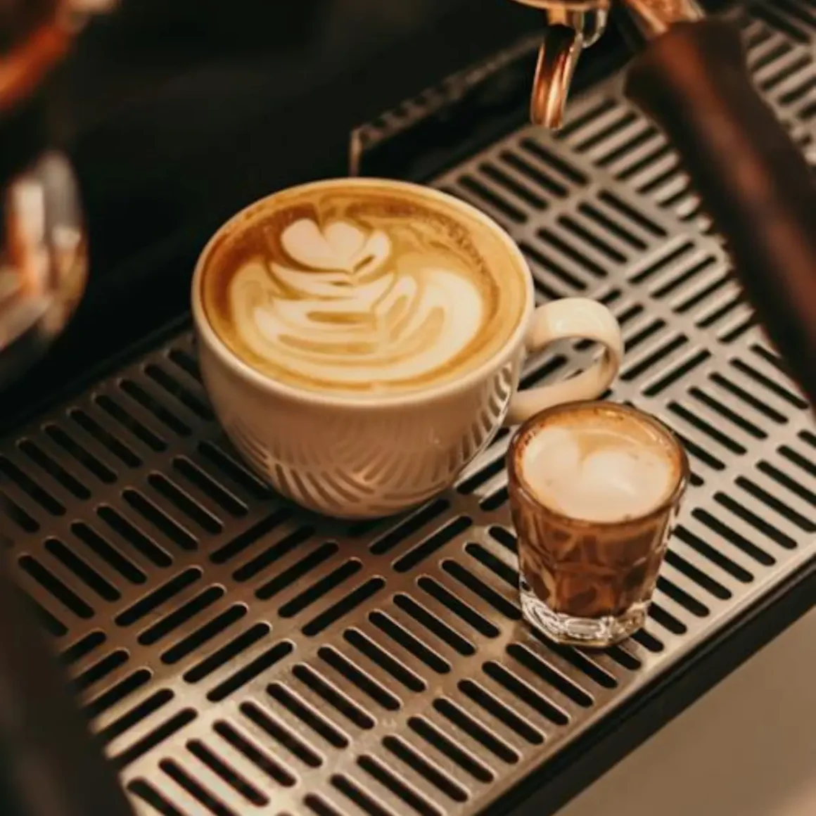a cup of and a shot glass of gibraltar coffee on a metal surface
