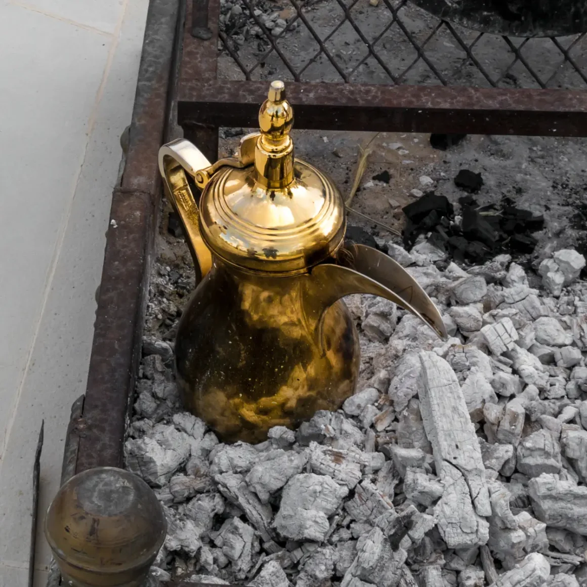 arabic coffee brewing in a gold pot in a pile of coal