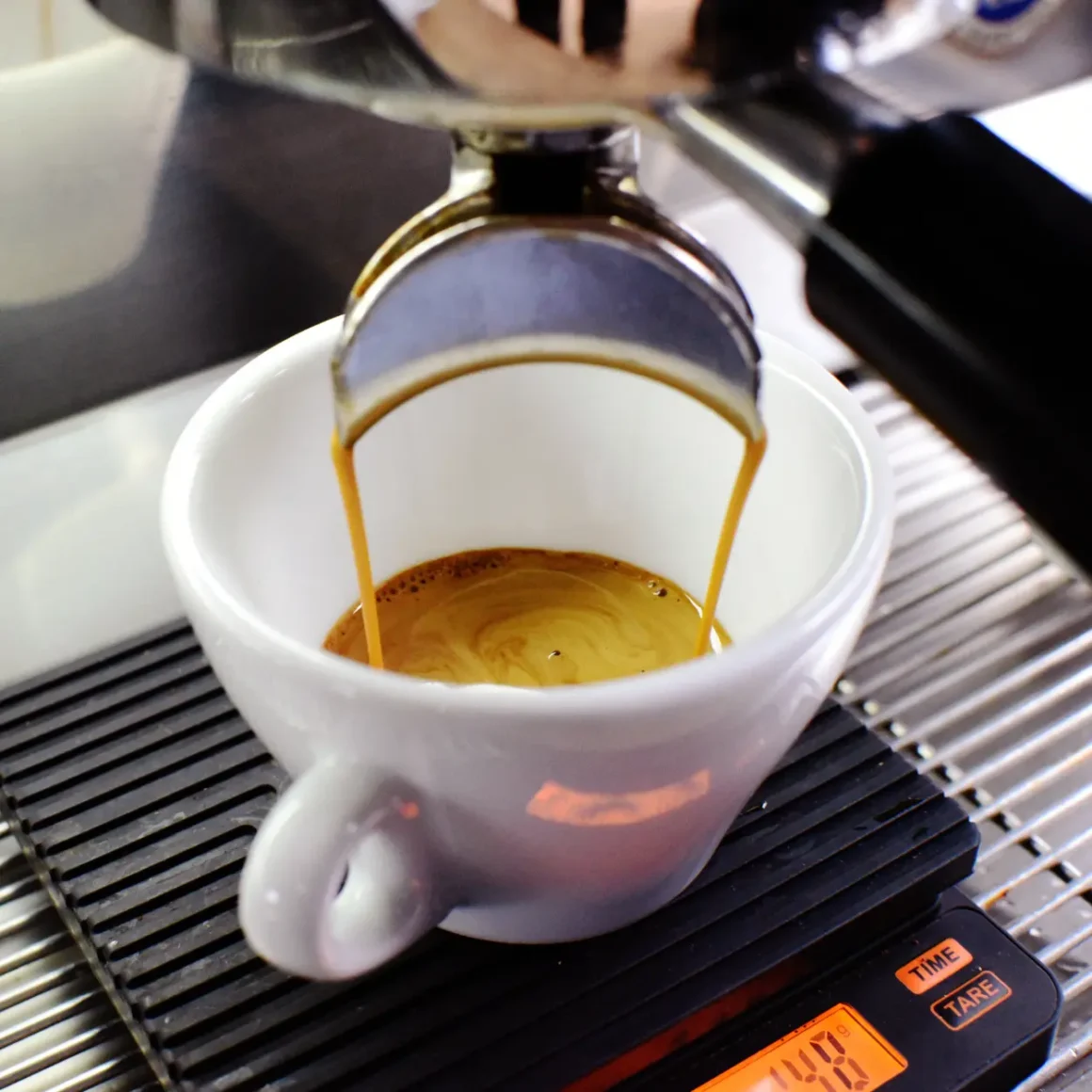 an espresso machine pouring coffee into a white cup