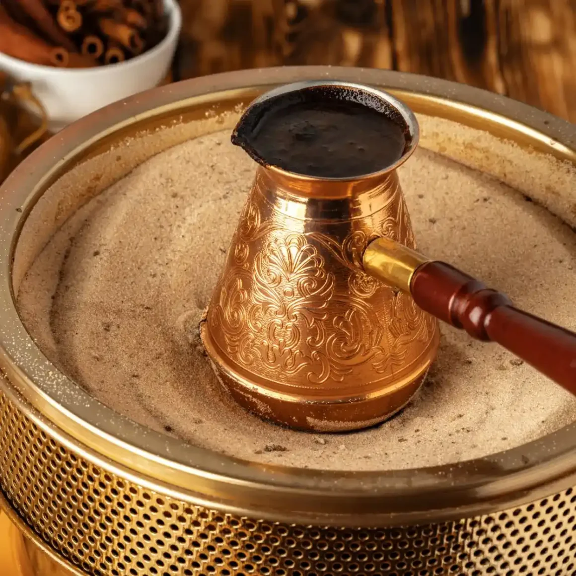 a turkish coffee pot with a handle on sand