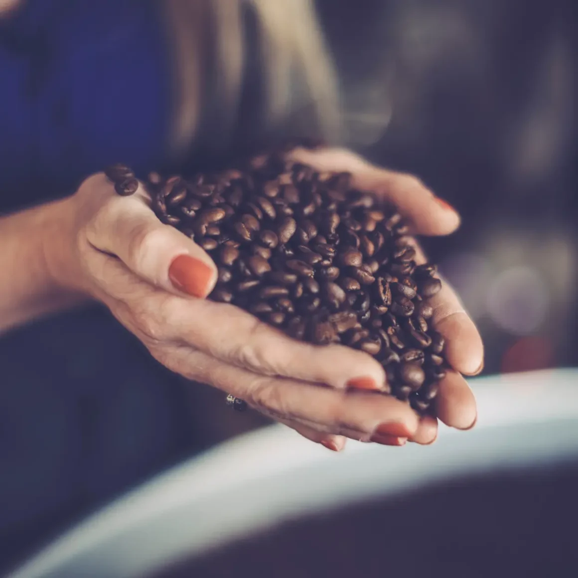 a person holding a handful of vienna roast coffee beans