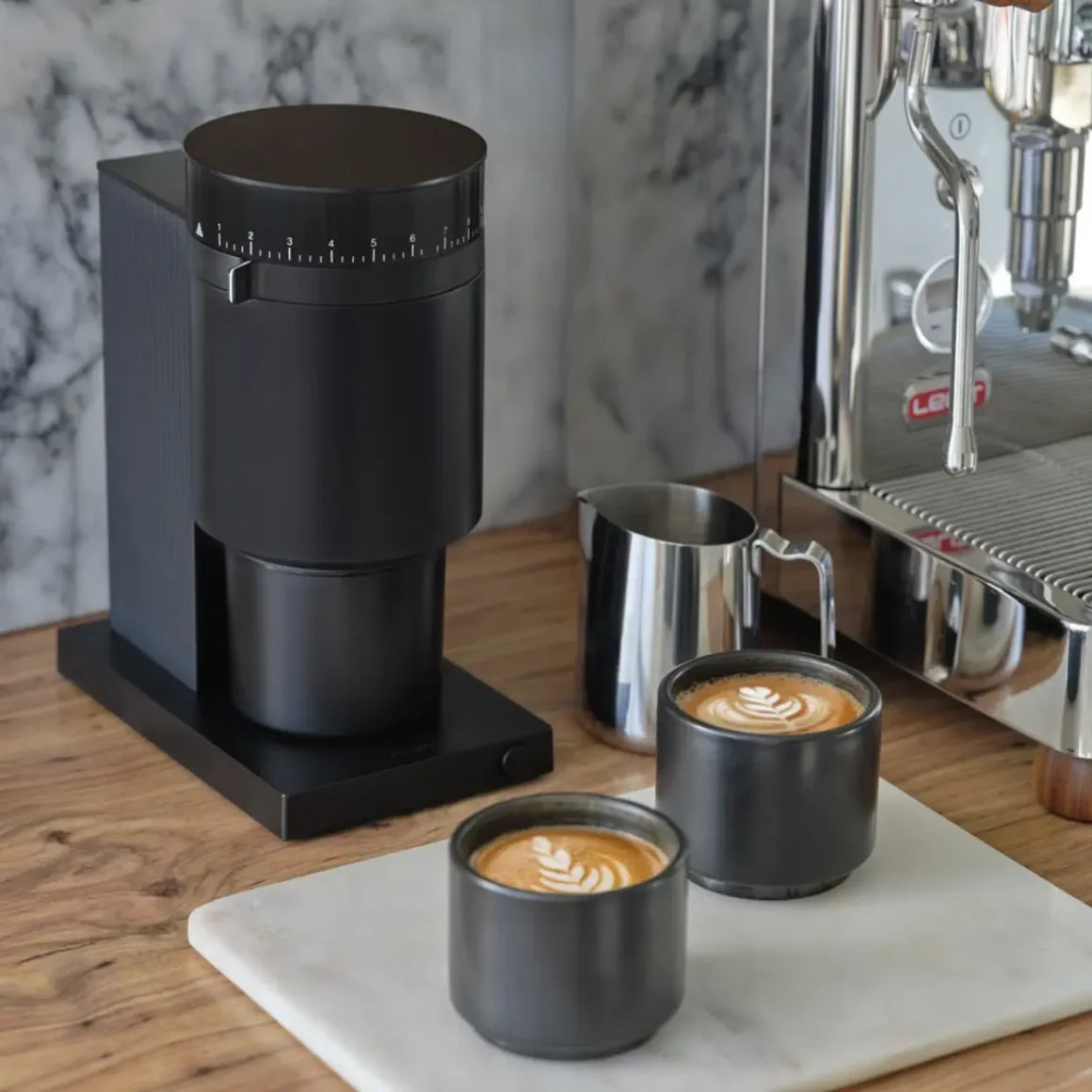 two cups of coffee next to a fellow opus coffee grinder