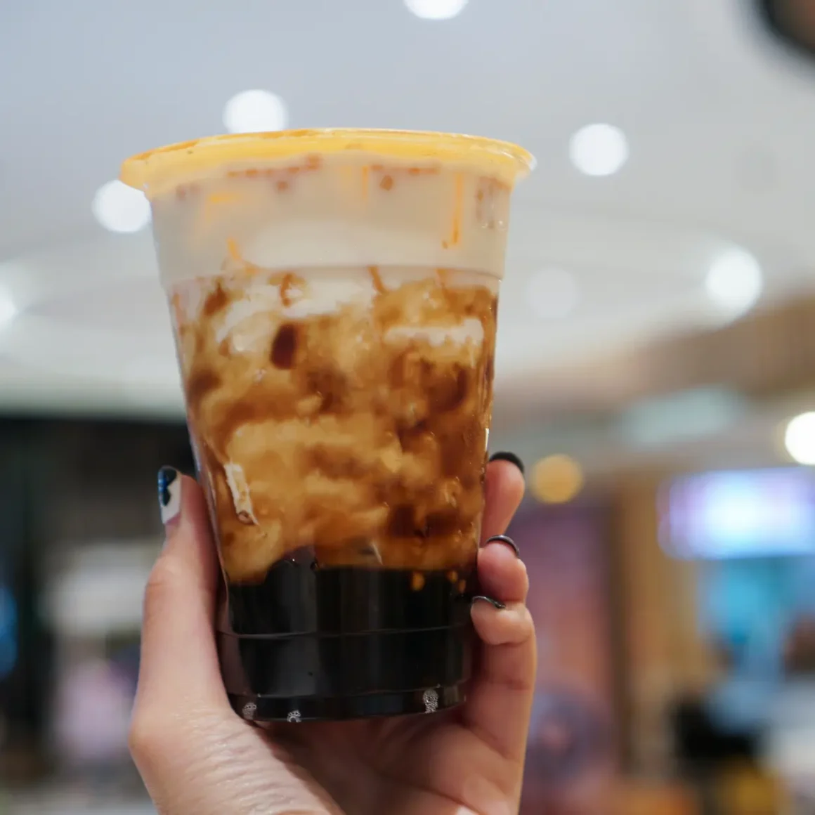 a hand holding a cup of brown sugar oatmilk shaken espresso