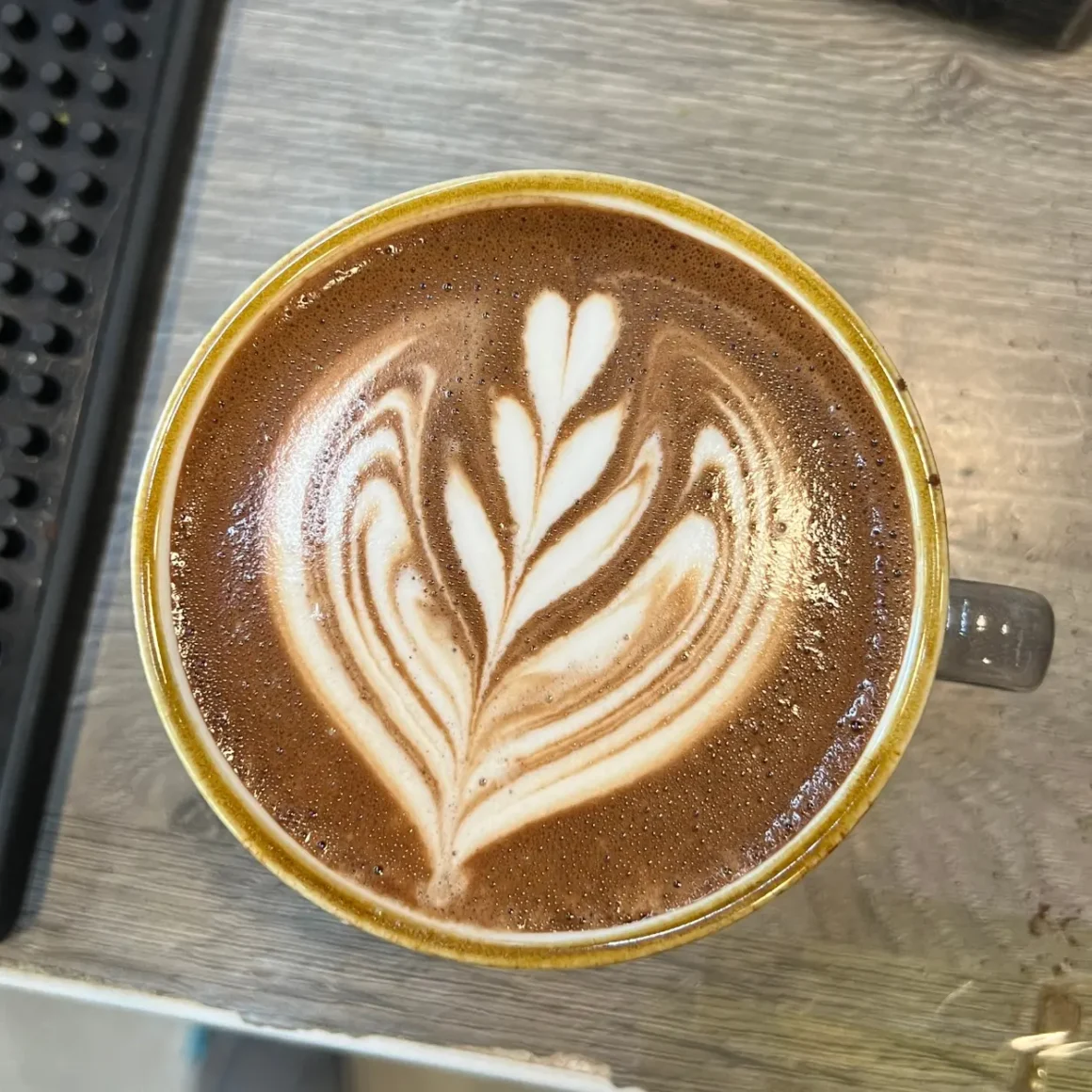 a cup of mocha coffee with a leaf design in the foam