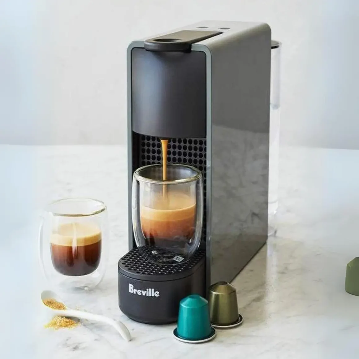 a nespresso essenza mini espresso machine with a glass of coffee