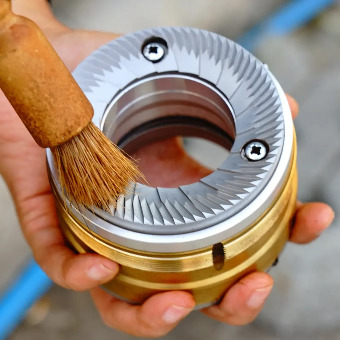 a person cleaning a burr of a coffee grinder with a brush