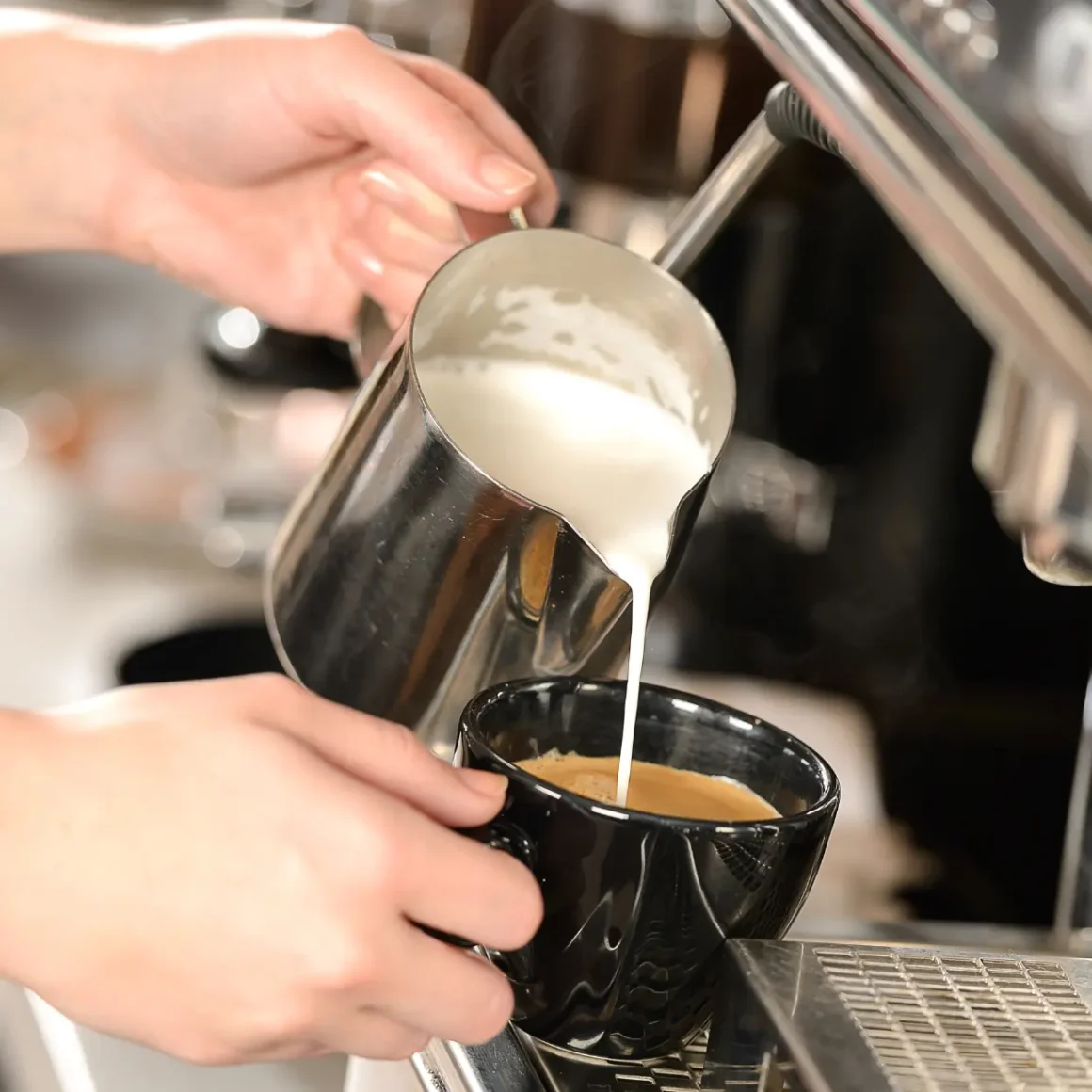 barista pouring milk into a cup