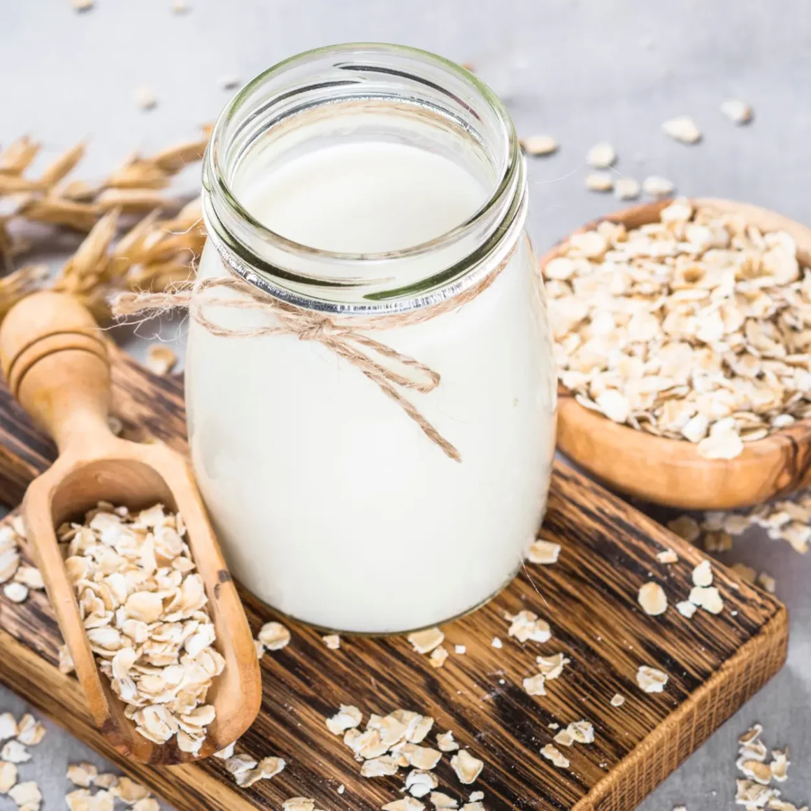 a glass jar of forthed milk and oats on a wooden board