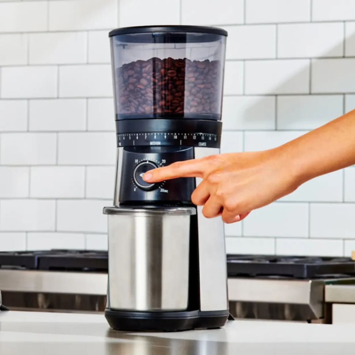 a hand pressing a switch of an oxo brew conical burr coffee grinder