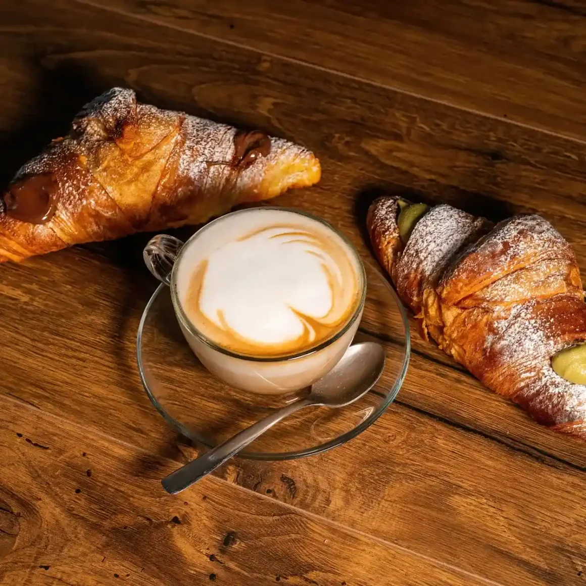a cup of café con leche coffee and croissants on a table
