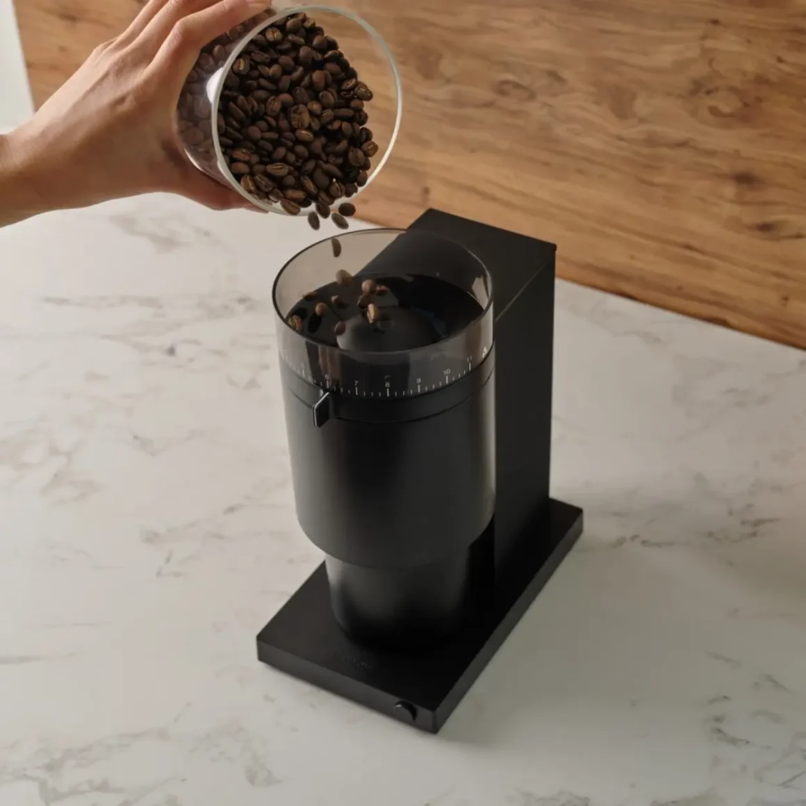 barista pouring coffee beans into a coffee grinder