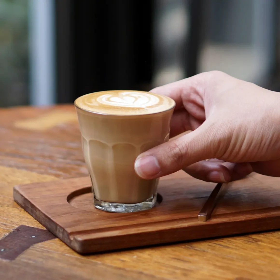 a hand holding a glass of piccolo coffee