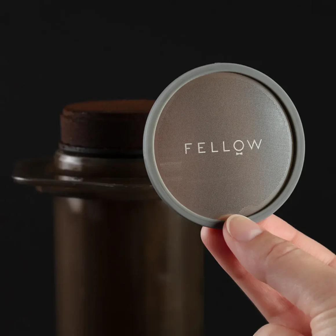 a hand holding fellow prismo coffee maker filter cap