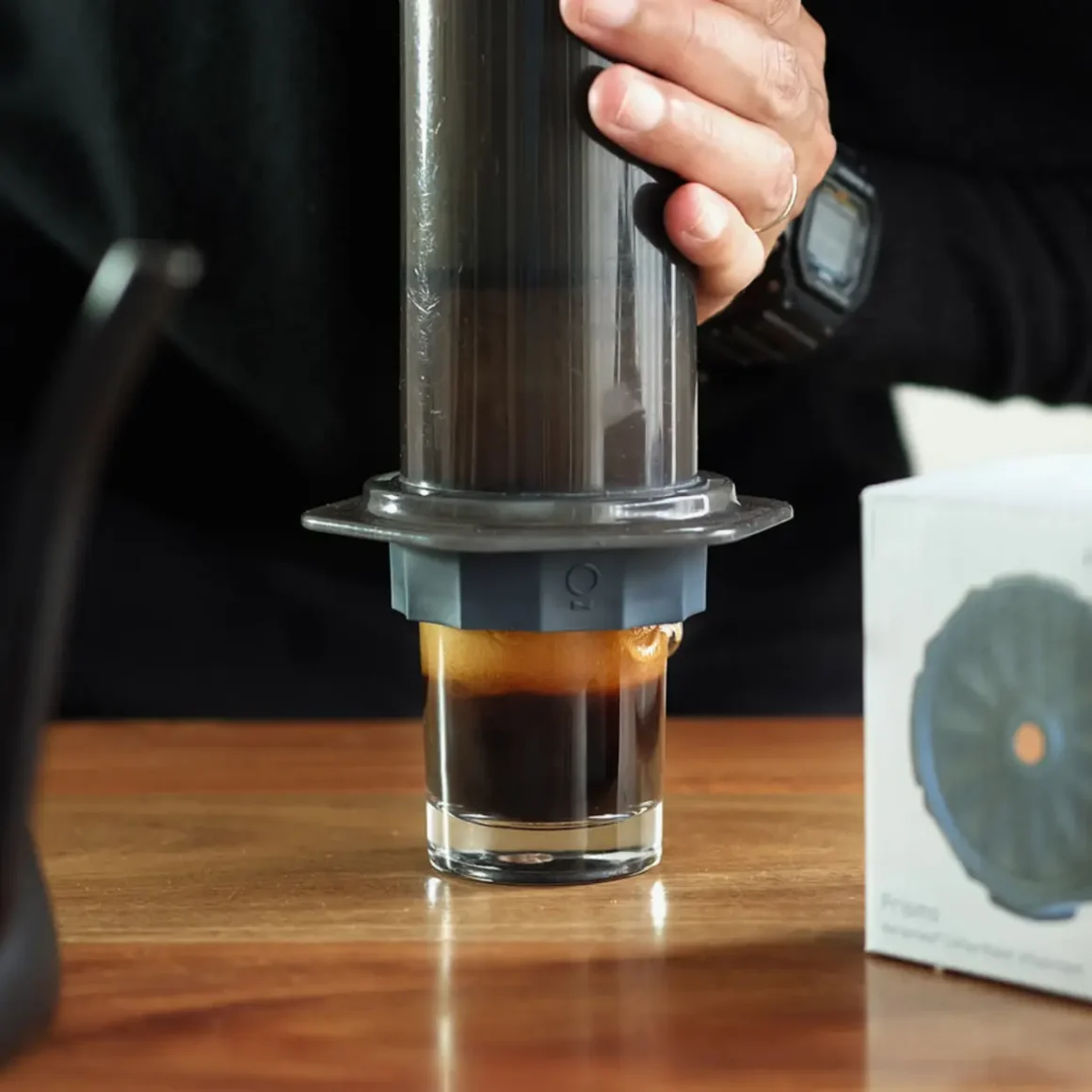 barista pouring coffee into a glass from a coffee maker