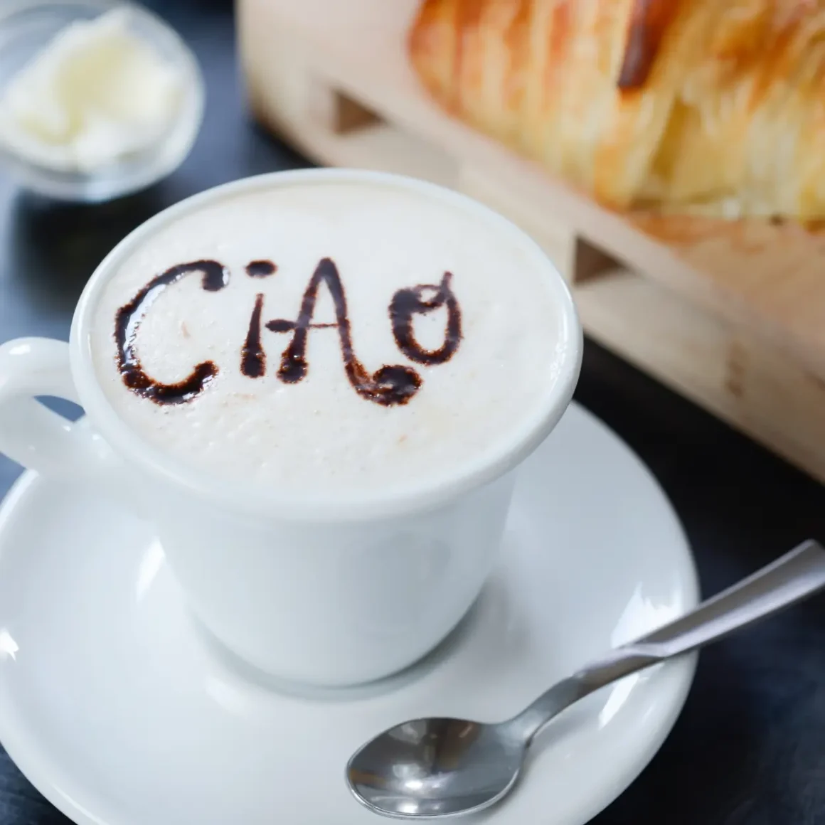 a cup of coffee with a croissant and a spoon