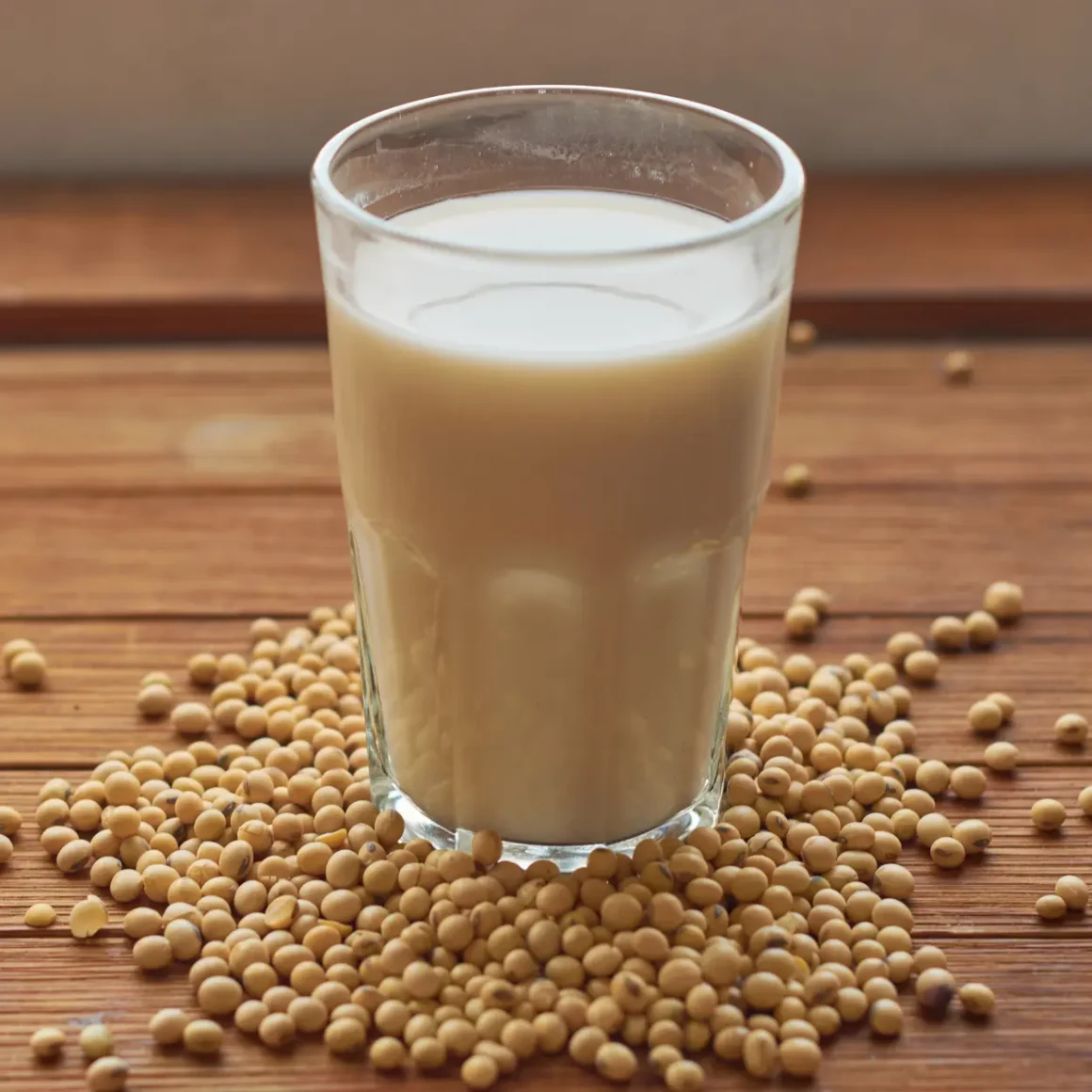 a glass of soy milk and soybeans on a table