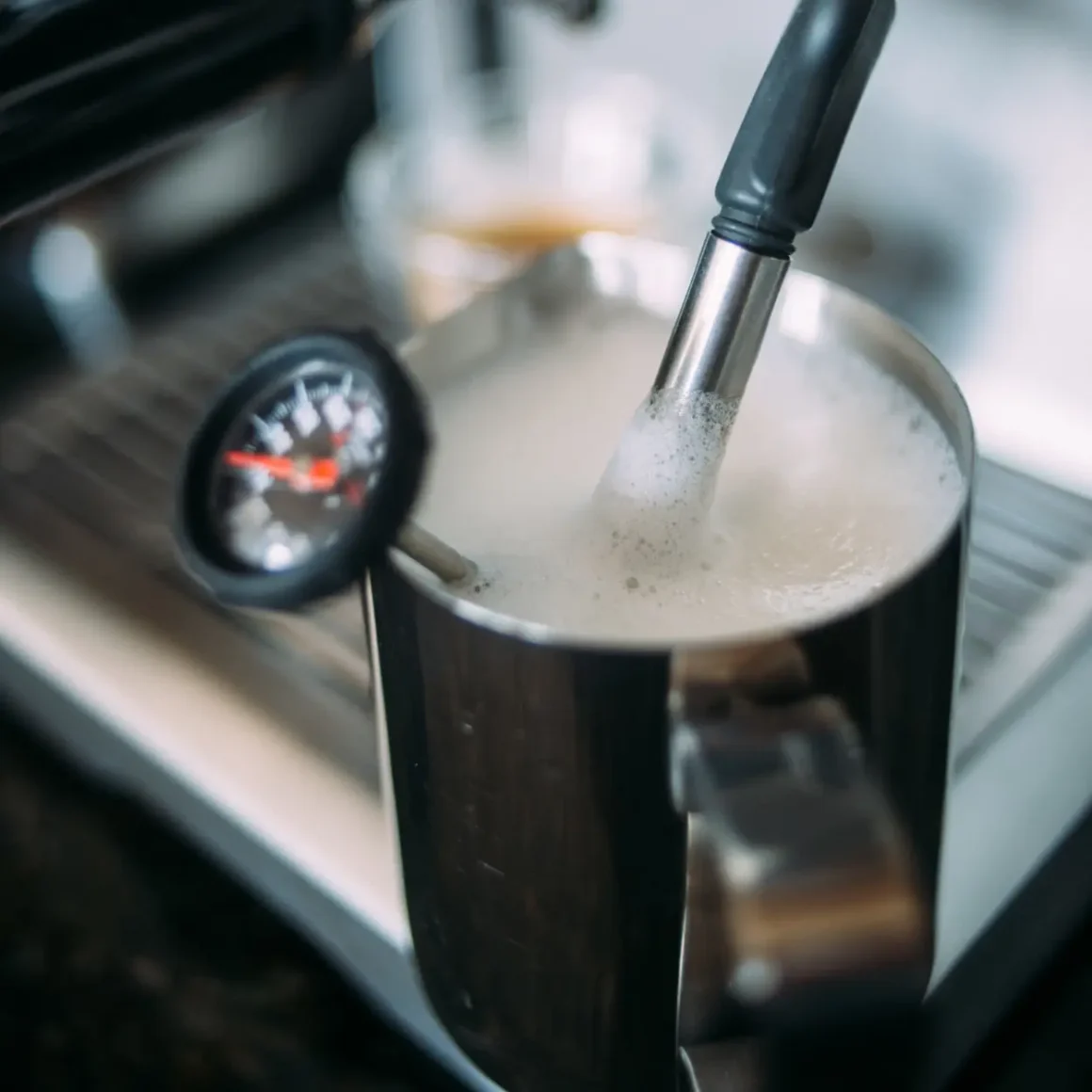 a metal mug with foam and a pressure gauge