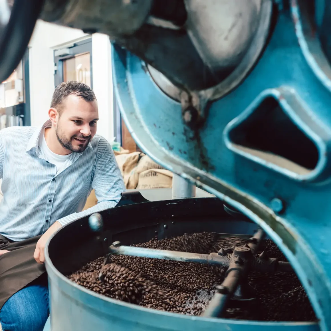 barista roasting coffee beans in a large machine