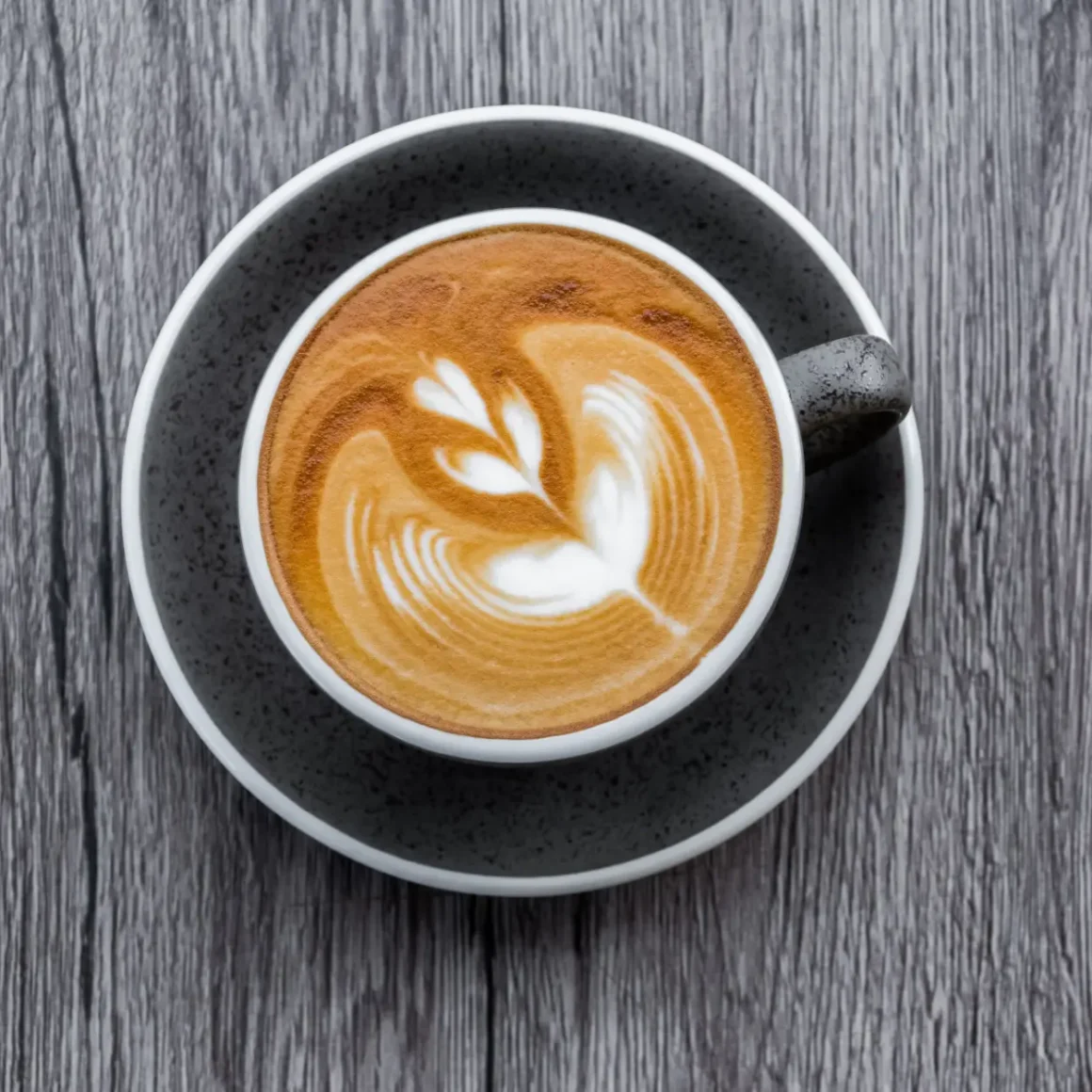 a cup of wet cappuccino coffee with a heart design in the foam