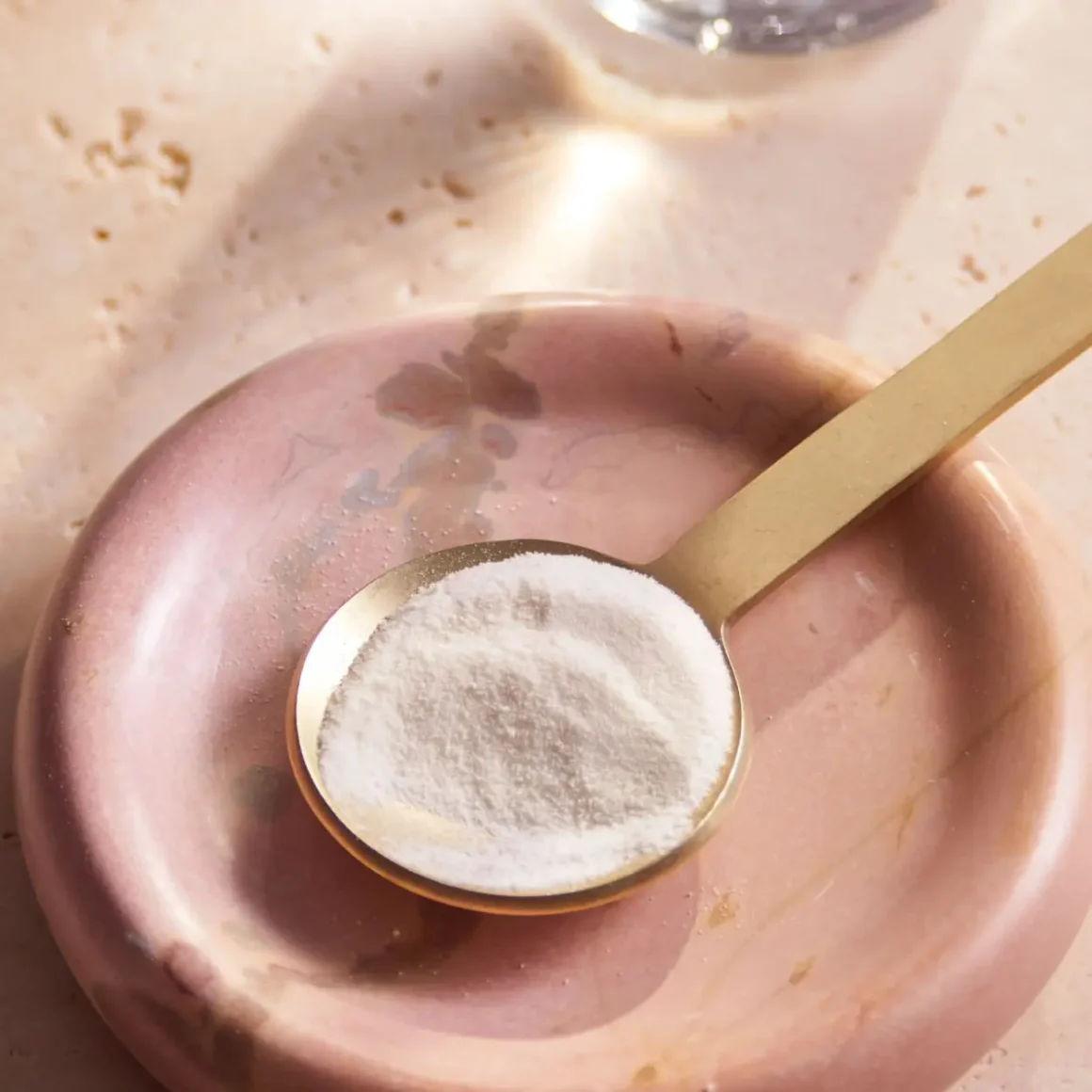 a spoonful of collagen coffee creamer on a pink plate
