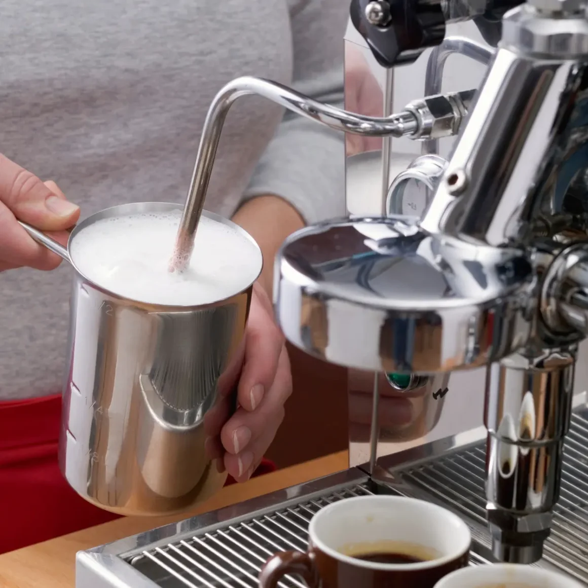 barista person pouring milk into a cup from an espresso machine