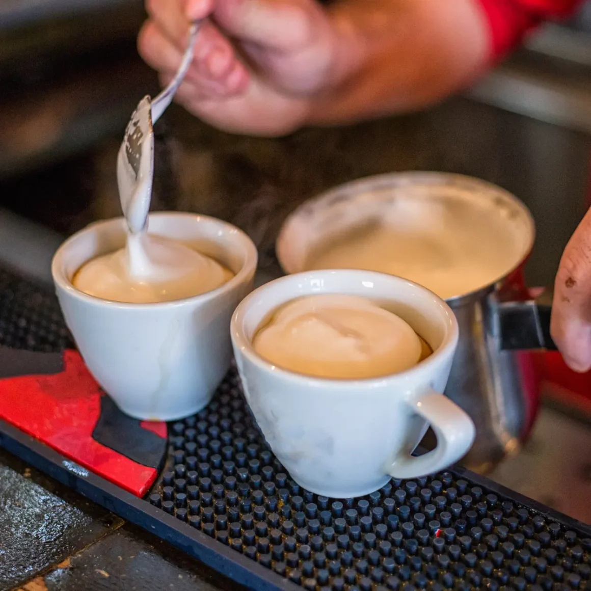 barista pouring dry cappuccino into cups