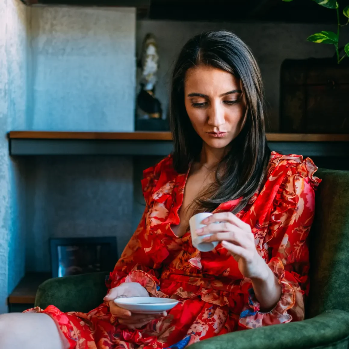a women in a red dress holding a cup of turkish coffee and a saucer