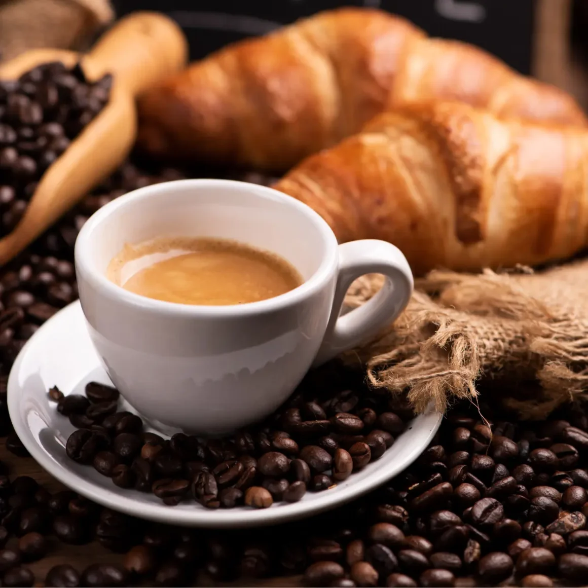 a cup of coffee and croissants with full city roast coffee beans