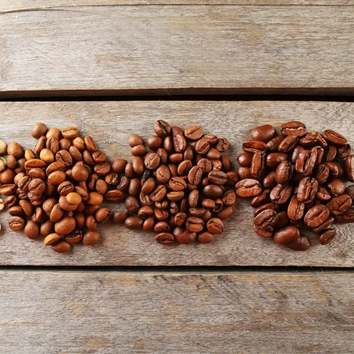 a group of coffee beans on a wood surface