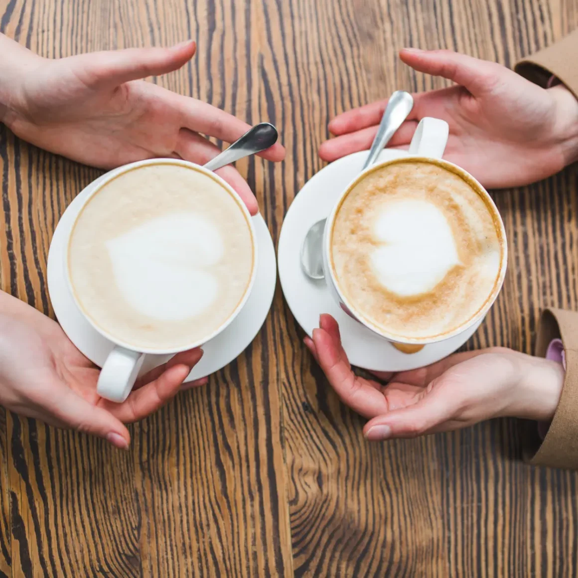 hands holding cups of wet cappuccino and dry cappuccino coffee