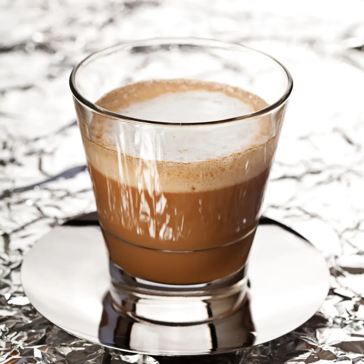 a glass of cortado coffee on a plate