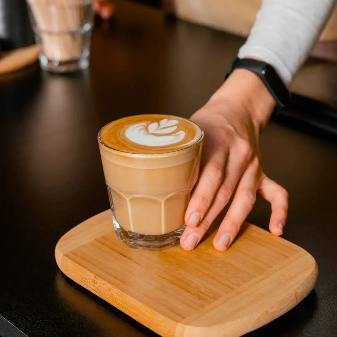 a hand holding a glass of cortado coffee