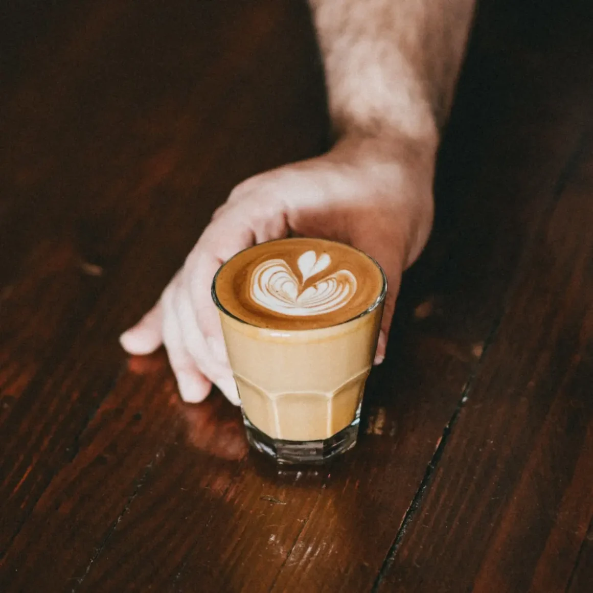 a hand holding a glass of gibraltar coffee