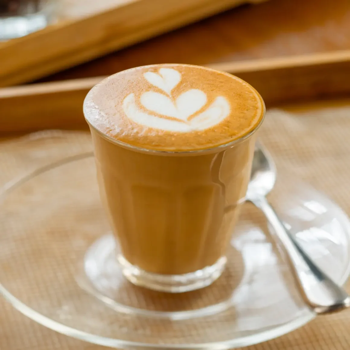 a glass cup of latte with a design on top