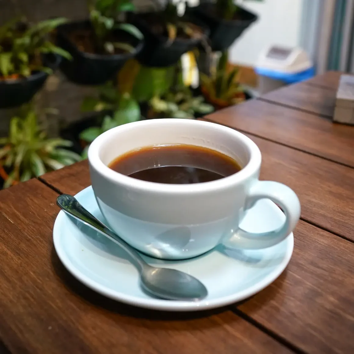 a cup of americano coffee on a saucer with a spoon