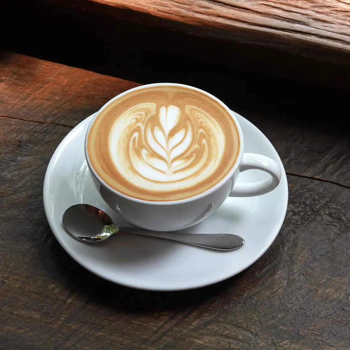 a cup of latte with a leaf design on top of it