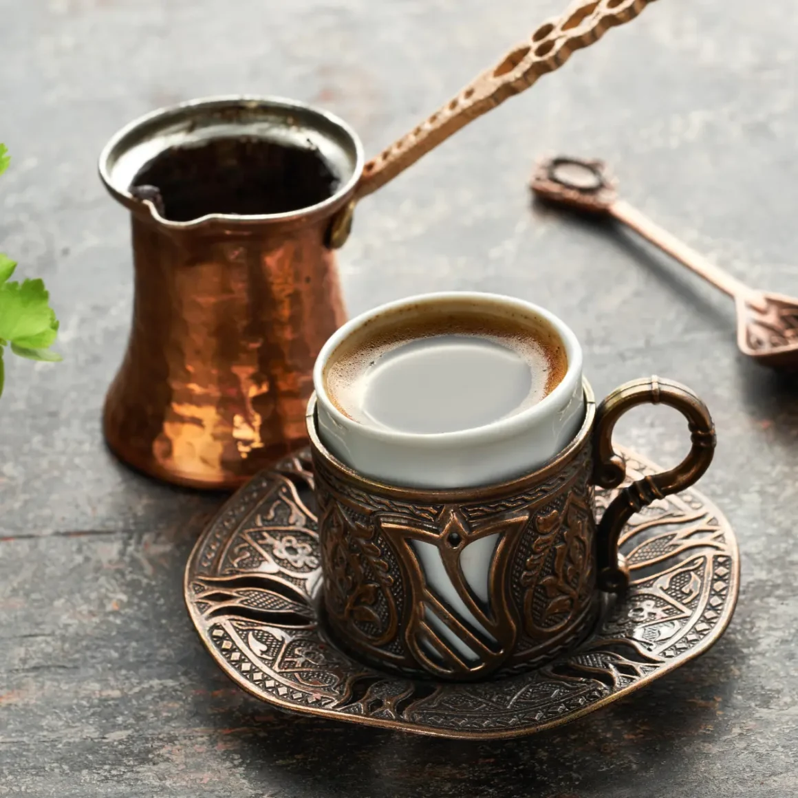 a cup of turkish coffee with a spoon and a pot