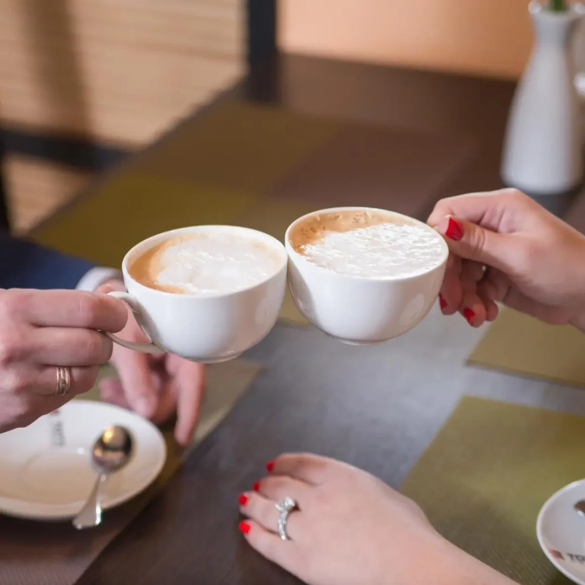 a couple of hands holding cups of dry cappuccino coffee