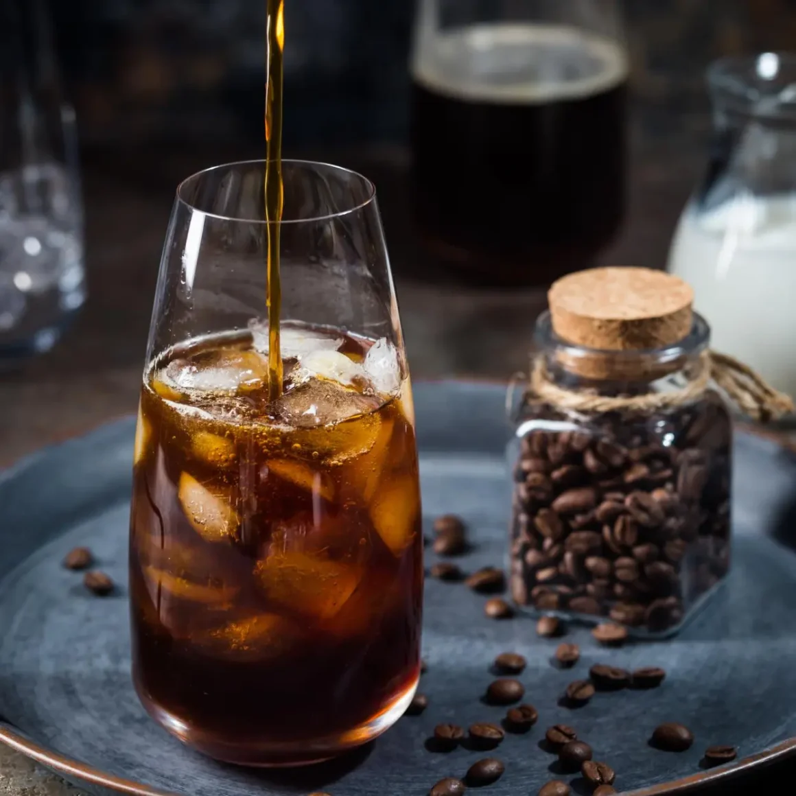 a double brewed coffee being poured into a glass with ice