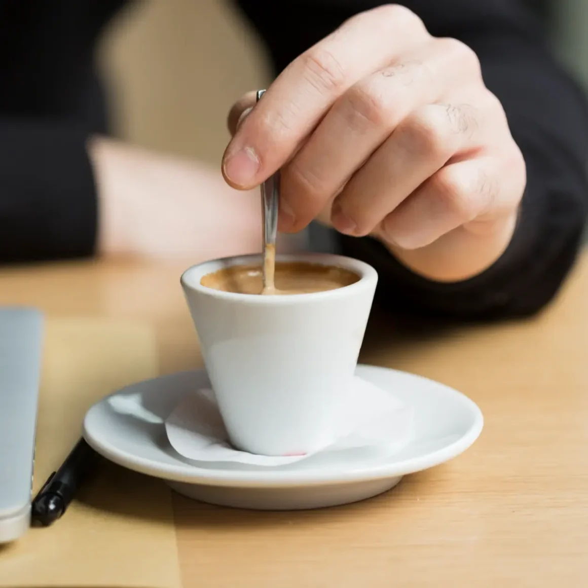 a cup of blonde espresso and a hand holding a spoon