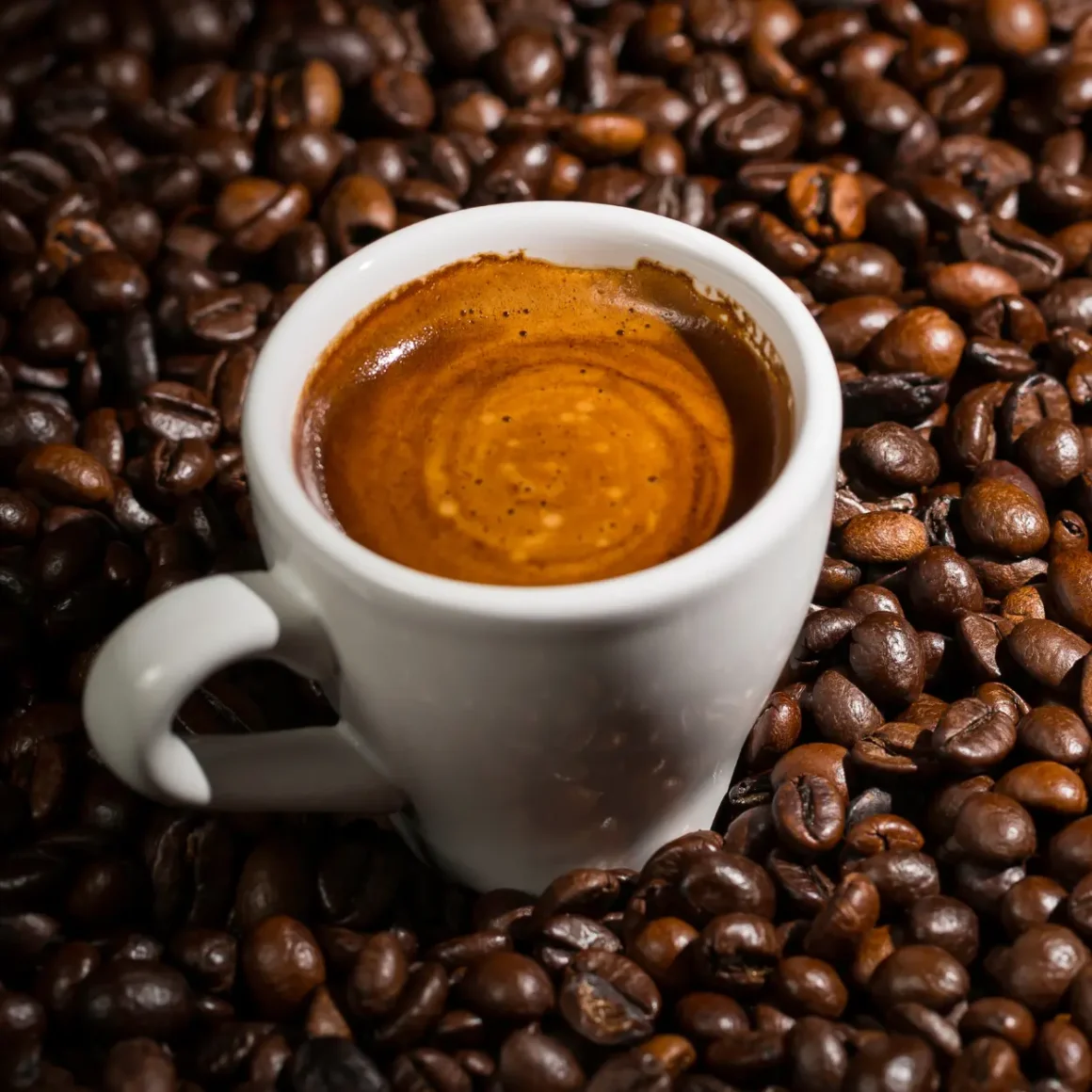 a cup of blonde espresso in a pile of coffee beans