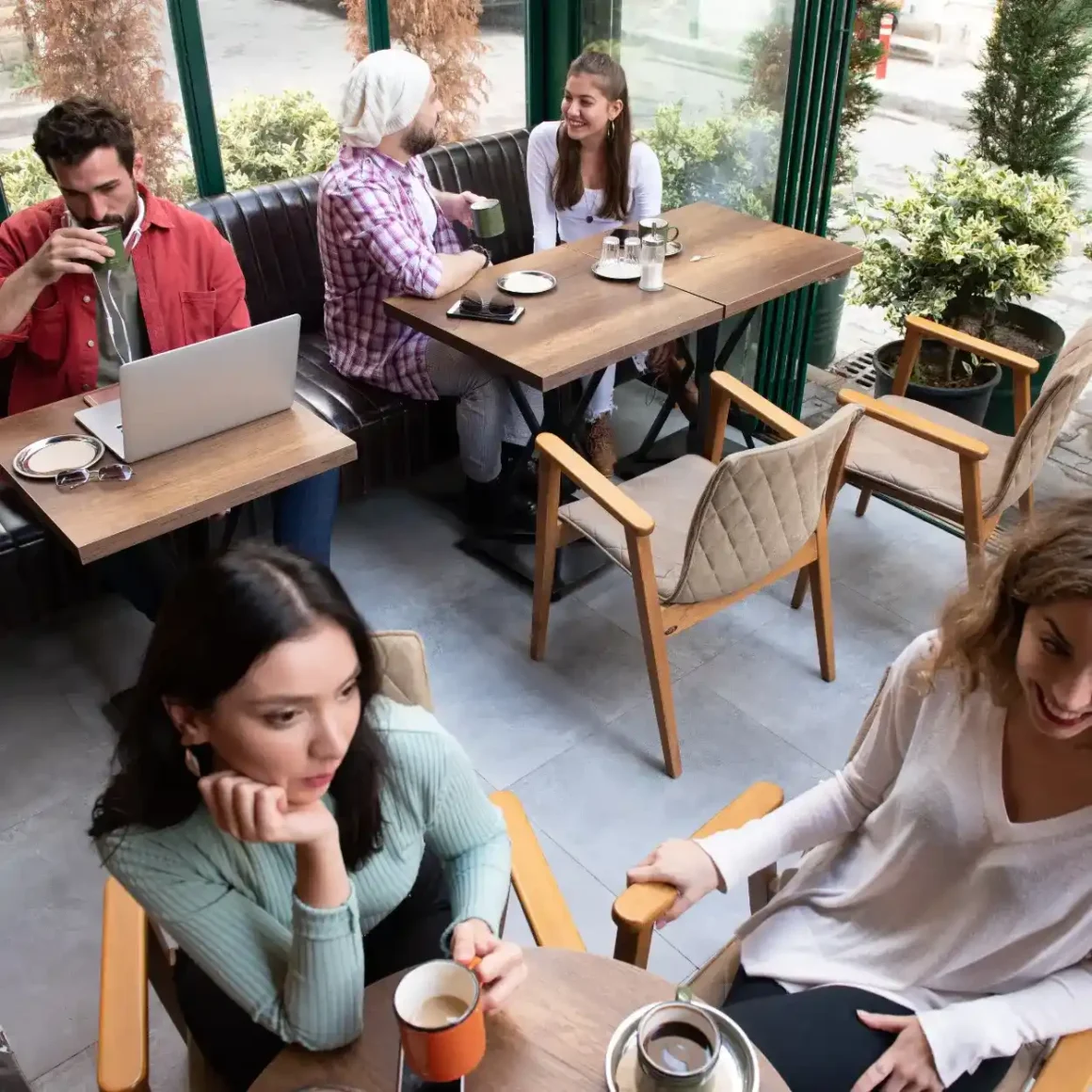 a group of people sitting at tables in a coffee shop