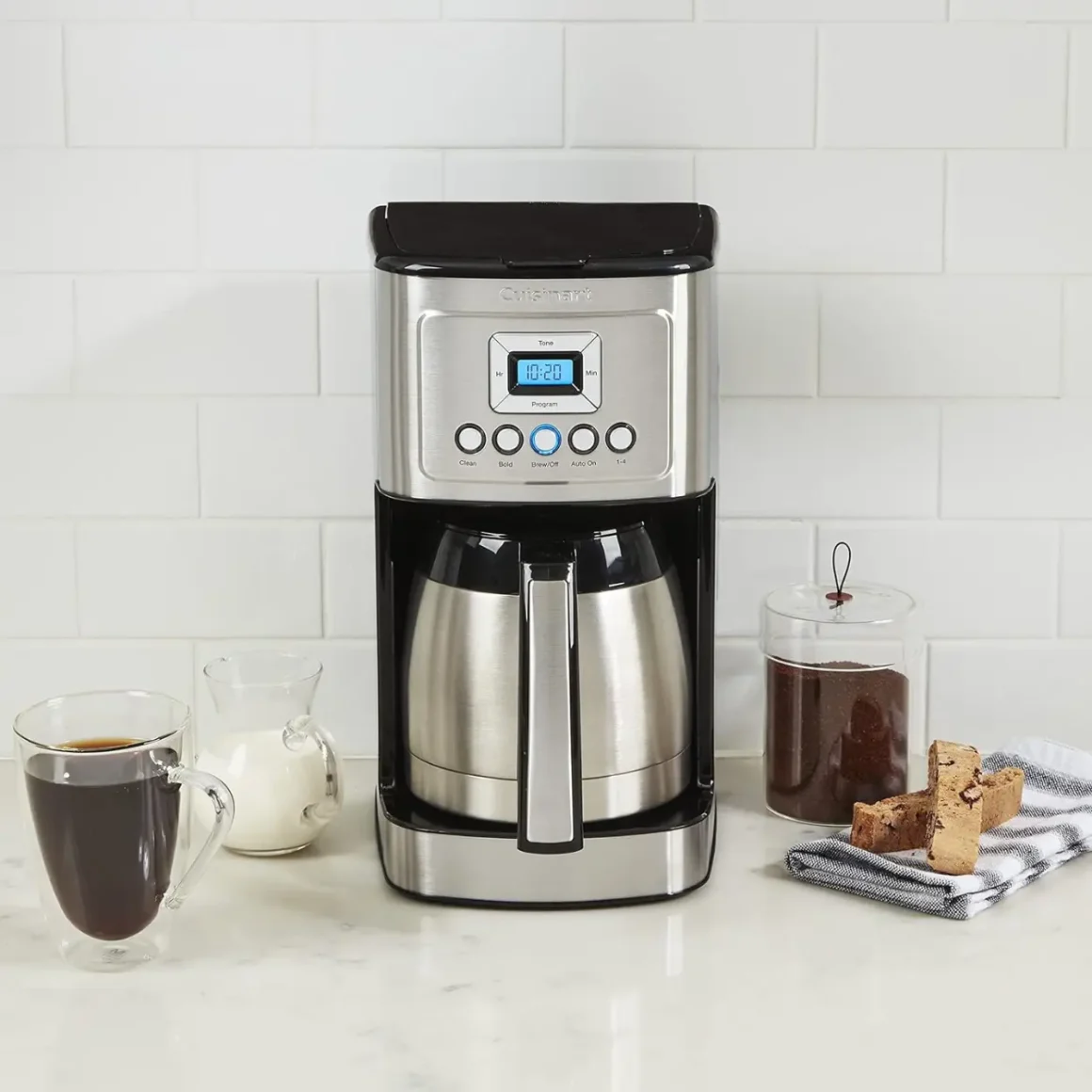 a cuisinart stainless steel 12-cup coffee maker and coffee mugs on a counter
