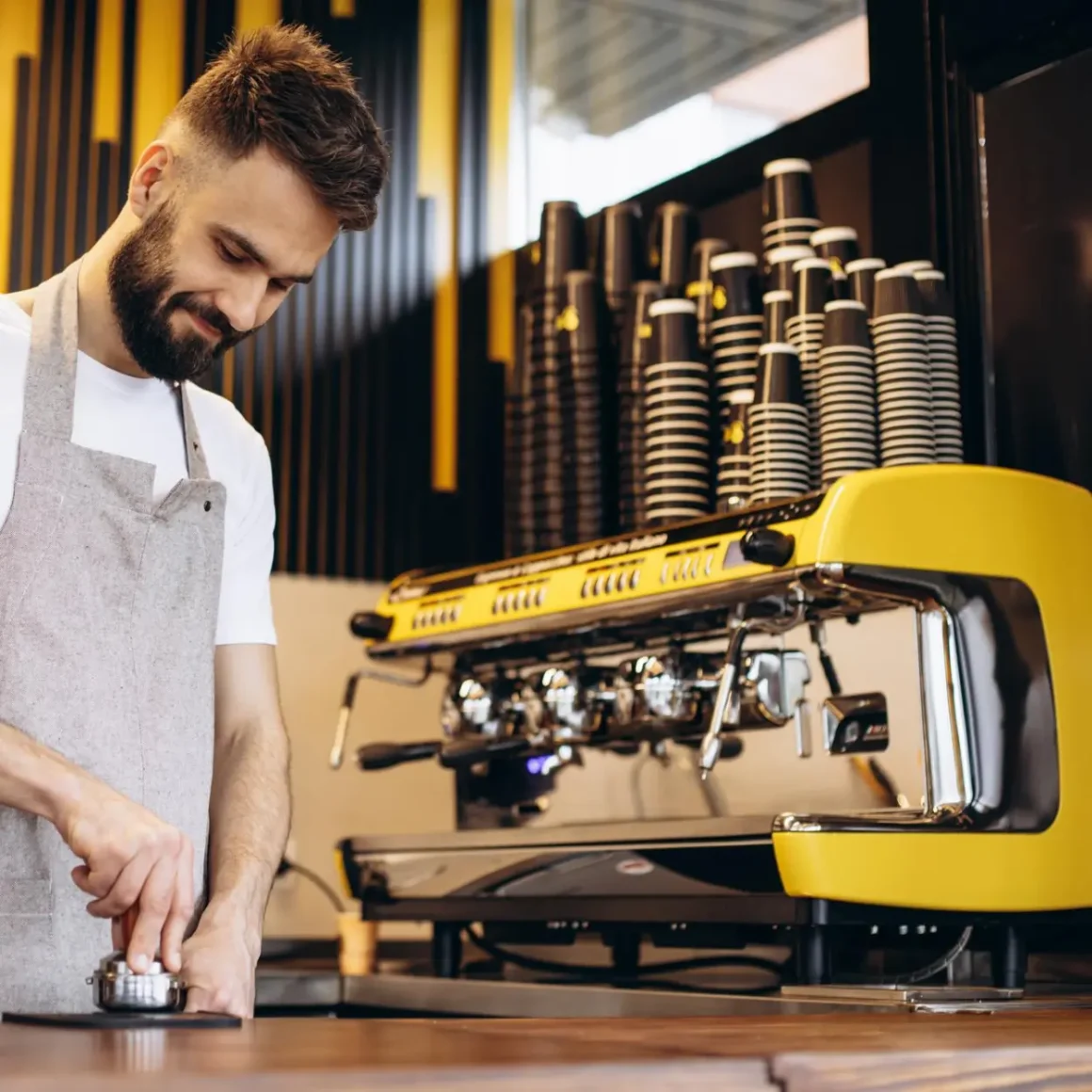 an espresso machine and barista in an apron brewing coffee