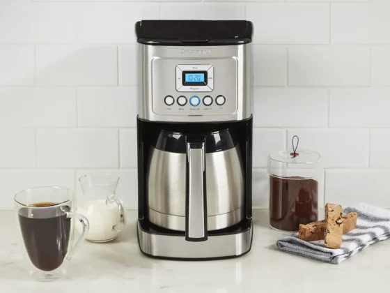 a cuisinart stainless steel 12-cup coffee maker and coffee mugs on a counter