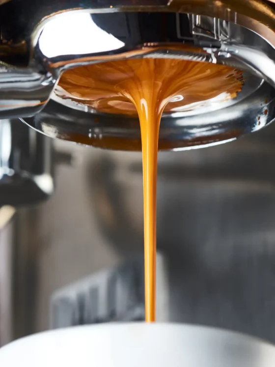 coffee is being poured from a bottomless portafilter into a cup